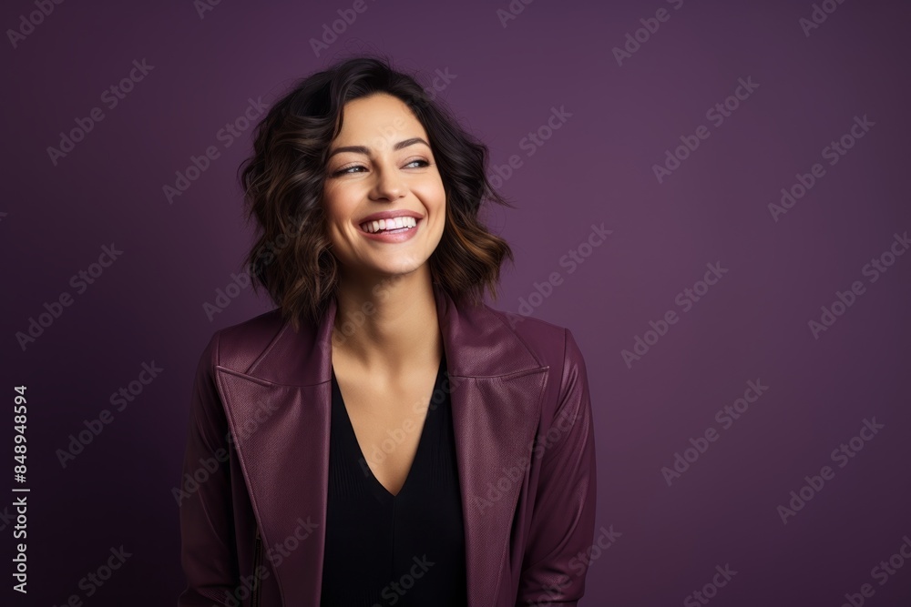 Portrait of a grinning woman in her 30s wearing a chic cardigan in front of solid color backdrop Portrait of a grinning woman in her 30s wearing a chic cardigan in front of solid color backdrop