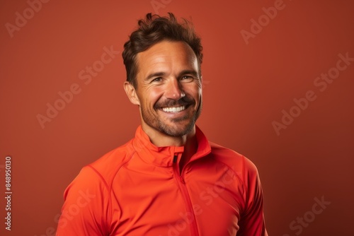 Portrait of a smiling man in his 30s sporting a technical climbing shirt in solid color backdrop