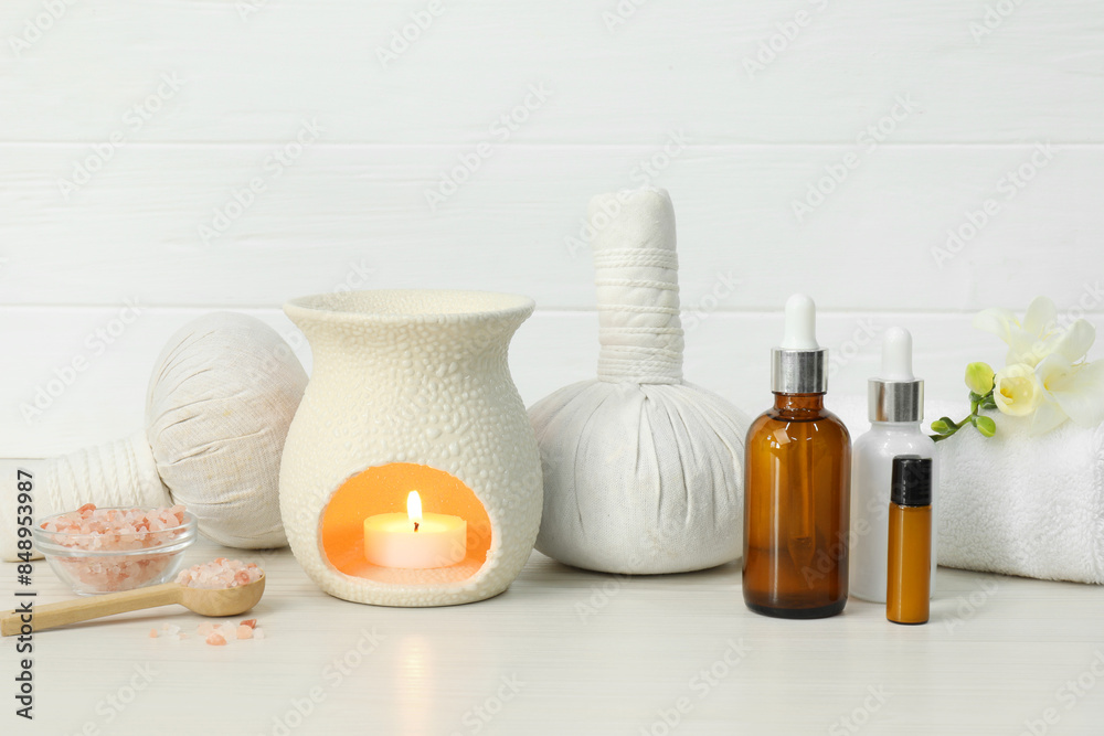 Different aromatherapy products and burning candle on white table Different aromatherapy products and burning candle on white table