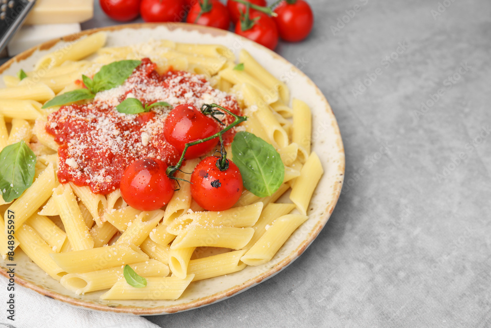 Tasty pasta with tomato sauce, cheese and basil on grey table, space for text Tasty pasta with tomato sauce, cheese and basil on grey table, space for text