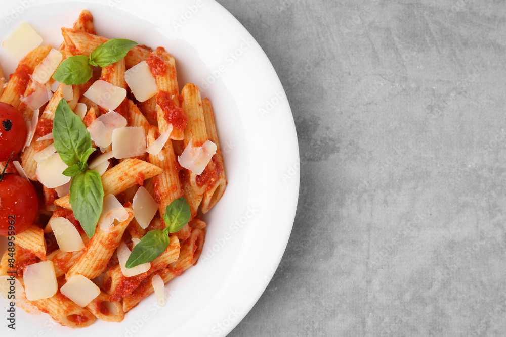 Tasty pasta with tomato sauce, cheese and basil on grey table, top view. Space for text