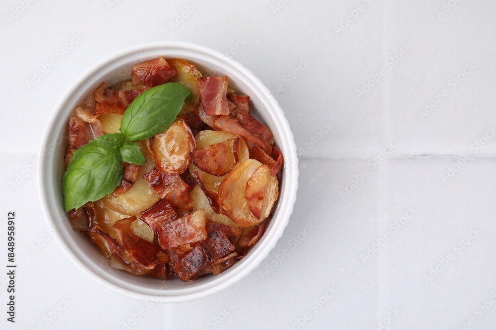 Delicious baked potatoes, bacon and basil in bowl on white table, top view. Space for text Delicious baked potatoes, bacon and basil in bowl on white table, top view. Space for text
