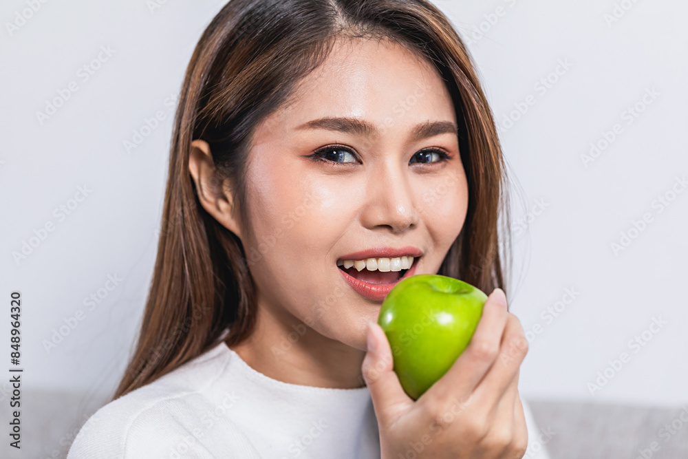 Young pretty woman eating red apple while sitting on the sofa at home Young pretty woman eating red apple while sitting on the sofa at home