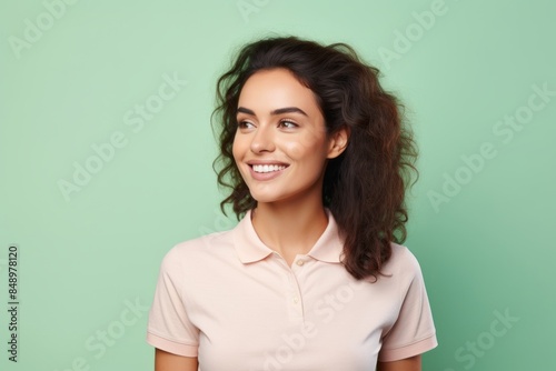 Portrait of a happy woman in her 20s wearing a sporty polo shirt isolated on solid pastel color wall © CogniLens
