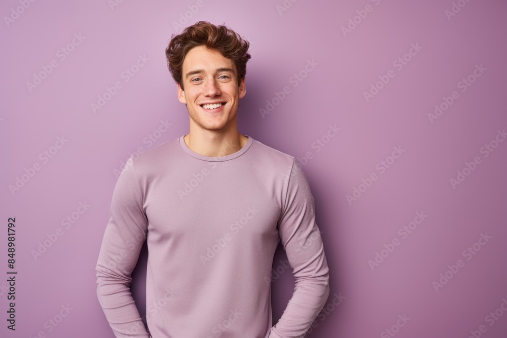 Portrait of a joyful man in his 20s showing off a lightweight base layer while standing against solid pastel color wall Portrait of a joyful man in his 20s showing off a lightweight base layer while standing against solid pastel color wall