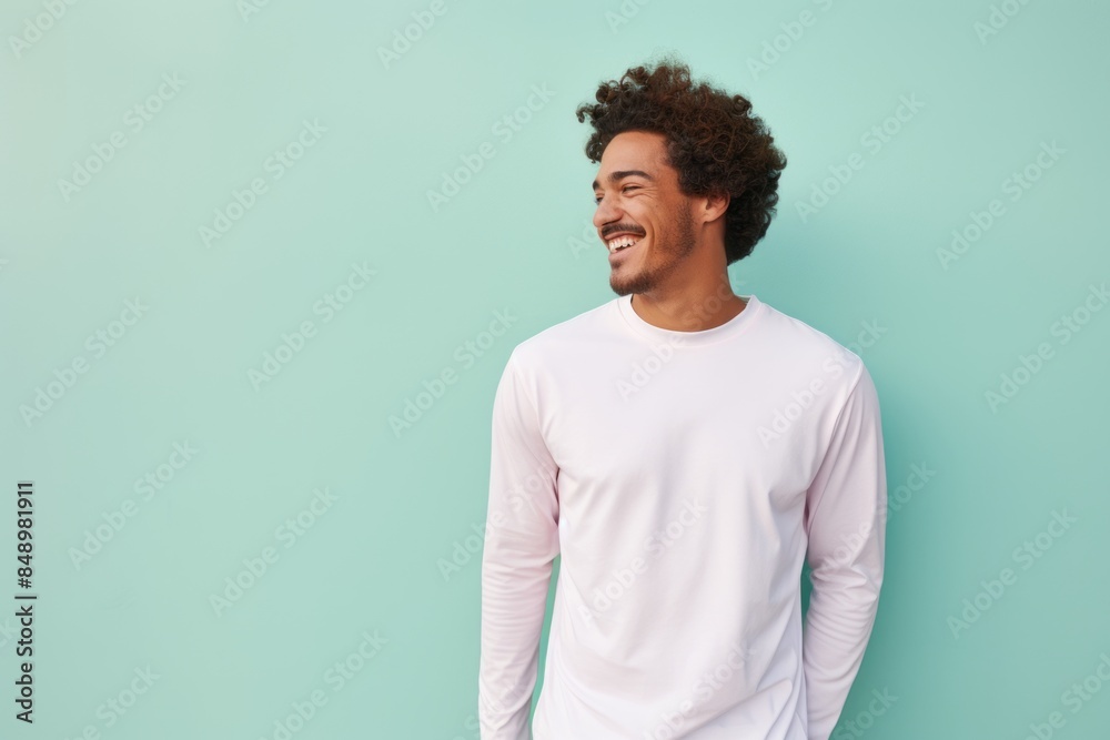 Portrait of a joyful man in his 20s showing off a lightweight base layer on solid pastel color wall Portrait of a joyful man in his 20s showing off a lightweight base layer on solid pastel color wall