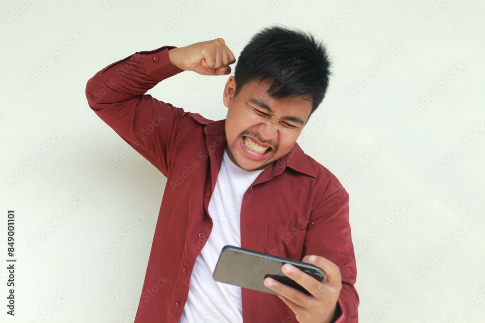 Angry Asian man plays mobile game on his smartphone. Angry Asian man plays mobile game on his smartphone.