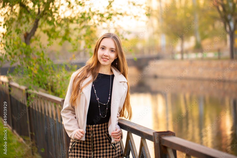 A young smiling girl walks through a spring park in a good mood. Teenage girl, portrait against a background of nature. Fashion style trend. A young smiling girl walks through a spring park in a good mood. Teenage girl, portrait against a background of nature. Fashion style trend.