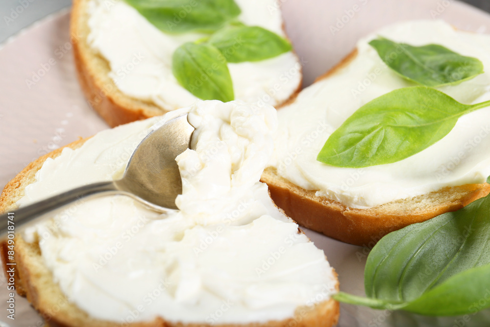 Delicious sandwiches with cream cheese and basil leaves on plate, closeup Delicious sandwiches with cream cheese and basil leaves on plate, closeup