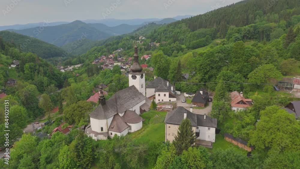 Flying over mountain village Spania Dolina in Slovakia. Aerial view of old church surrounded by forests and mountains in Spania Dolina Flying over mountain village Spania Dolina in Slovakia. Aerial view of old church surrounded by forests and mountains in Spania Dolina