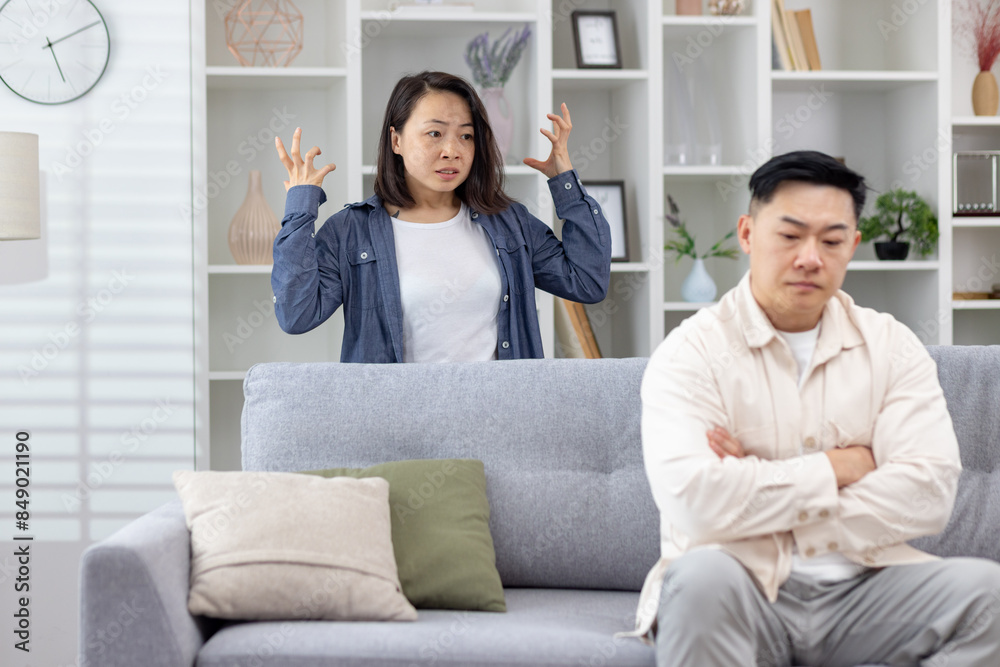 Young couple having an argument in their living room, showcasing stress and relationship issues. Young couple having an argument in their living room, showcasing stress and relationship issues.