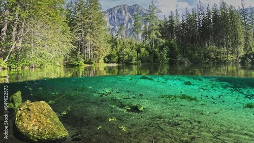 Half underwater dome shot of Green Lake - Gruner See - in Austria. Camera plunges into the water of lake with green bottom, Alps mountains in the background