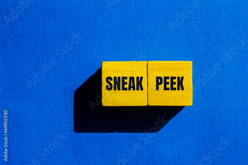 Sneak peek message written on yellow wooden cubes with blue background. Conceptual sneak peek symbol. Copy space. photo