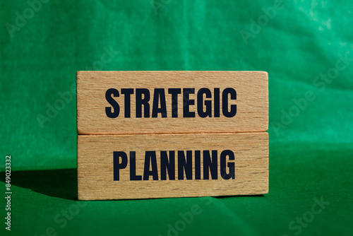 Strategic planning message written on wooden blocks with green background. Conceptual strategic planning symbol. Copy space.