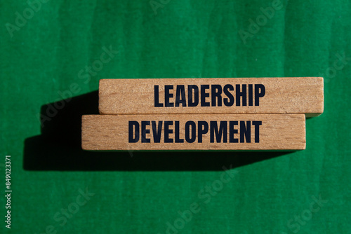 Leadership development message written on wooden blcoks with green background. Conceptual leadership development symbol. Copy space. photo