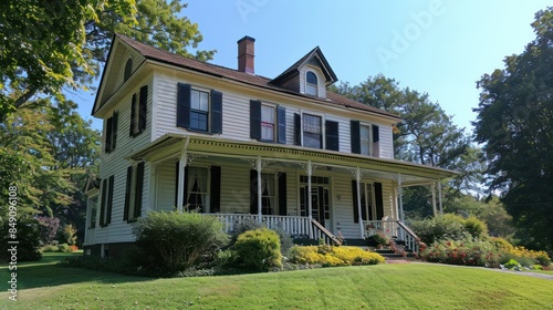 A large white house with a red door sits in a lush green yard