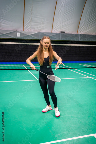 Sports young woman with racket and shuttlecock is exercising, playing in badminton on inside court