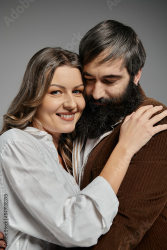 A loving couple poses together, the woman smiling warmly as she rests her head on her bearded partners shoulder.