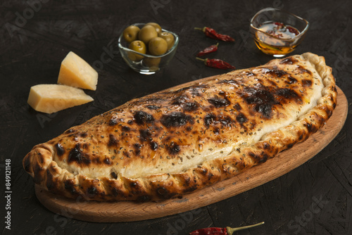 Traditional calzone pizza  with cheese and olives on black background.