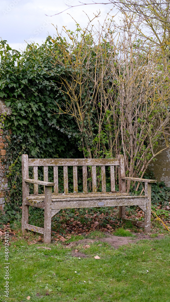 Wooden park bench seat with nobody sitting on it located in English rural countryside garden