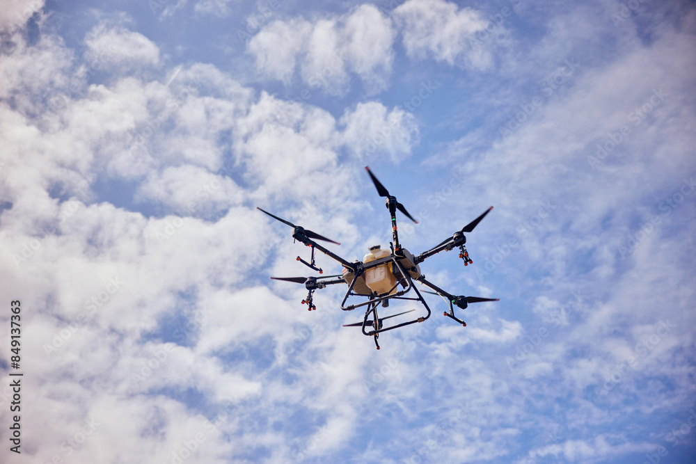 An agro drone flying in the sky, during the blooming season, spraying fields. An agro drone flying in the sky, during the blooming season, spraying fields.