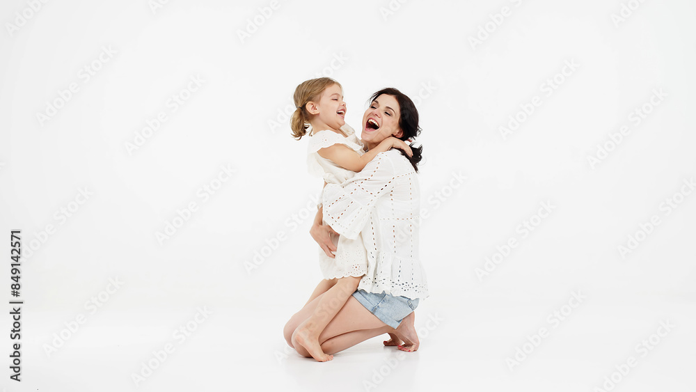 Happy mother and daughter playing and having fun on a white background. Concept of a happy family, motherhood, style and fashion. Happy mother and daughter playing and having fun on a white background. Concept of a happy family, motherhood, style and fashion.