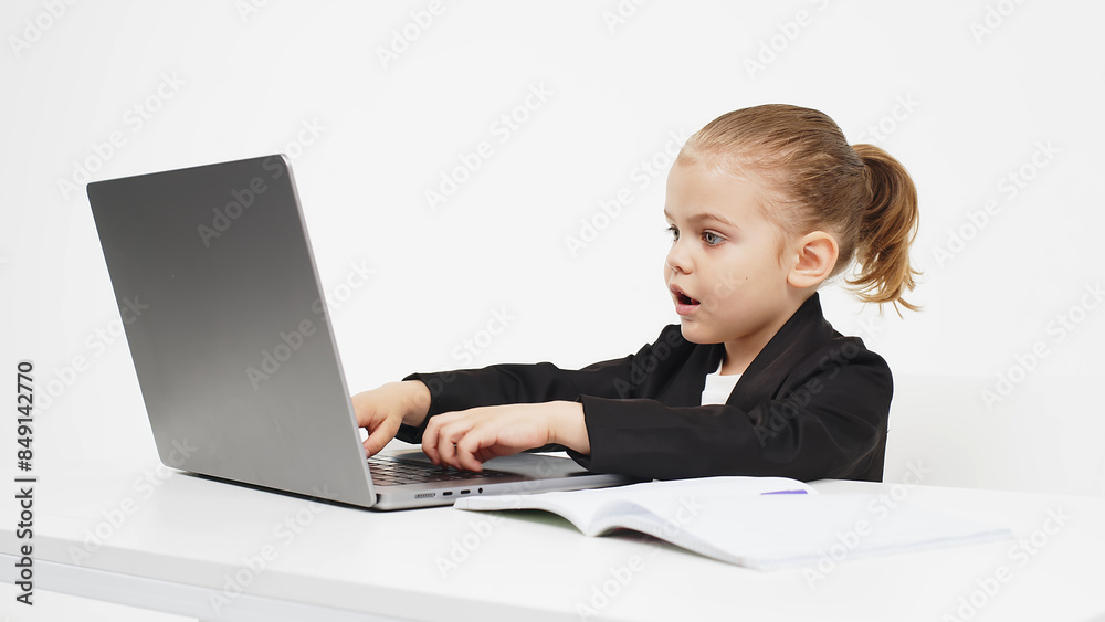 Business, little child working at a laptop on a light isolated studio background. Concept of deal, business and modern technology. Business, little child working at a laptop on a light isolated studio background. Concept of deal, business and modern technology.