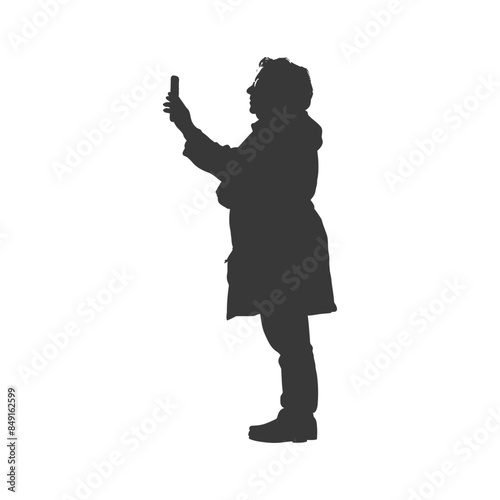 Silhouette of woman in coat taking a cell phone photo.