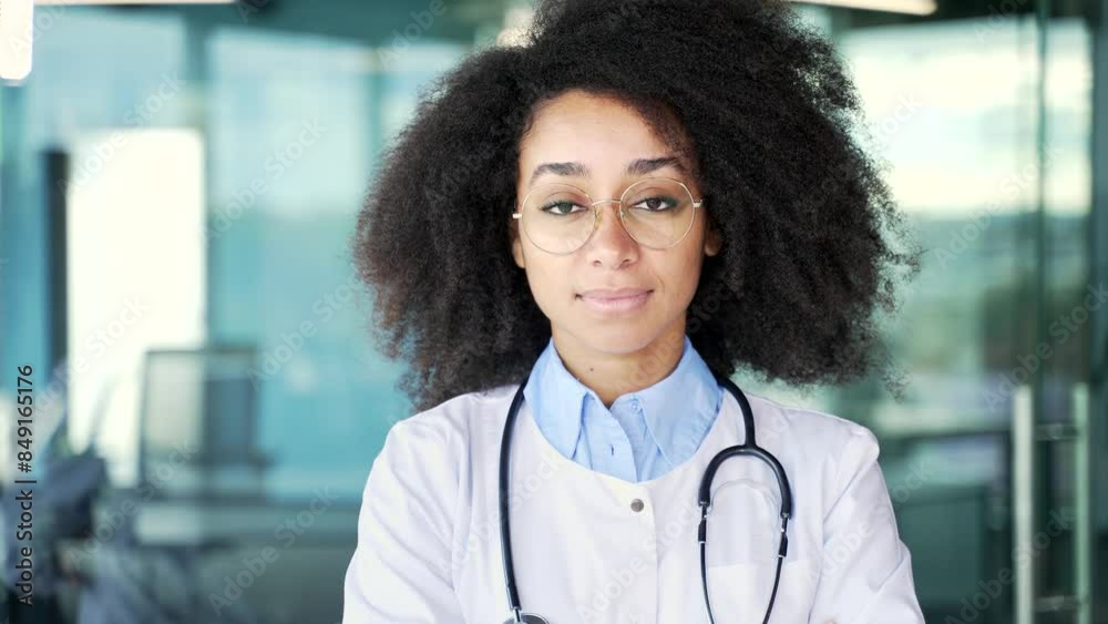 Portrait of serous young african american female doctor in white coat with stethoscope looking at camera in modern hospital clinic. Black woman medical worker physician standing in office. Close up Portrait of serous young african american female doctor in white coat with stethoscope looking at camera in modern hospital clinic. Black woman medical worker physician standing in office. Close up