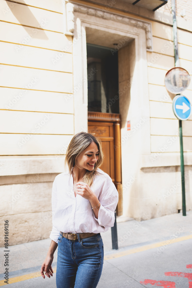 A woman in jeans and shirt strolls happily through her city on a sunny day. A woman in jeans and shirt strolls happily through her city on a sunny day.