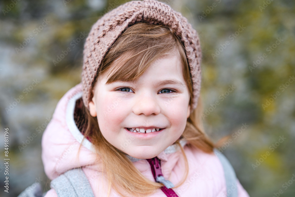 Portrait of happy smiling toddler girl outdoors. Little child with blond hairs looking and smiling at the camera. Happy healthy child enjoy outdoor activity and playing. Portrait of happy smiling toddler girl outdoors. Little child with blond hairs looking and smiling at the camera. Happy healthy child enjoy outdoor activity and playing.