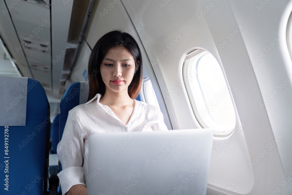 Businesswoman Working on Laptop During Airplane Travel, Professional Woman in Modern Air Travel Setting, Corporate Travel, Business Trip, In flight Productivity, Efficient Business Travel Businesswoman Working on Laptop During Airplane Travel, Professional Woman in Modern Air Travel Setting, Corporate Travel, Business Trip, In flight Productivity, Efficient Business Travel