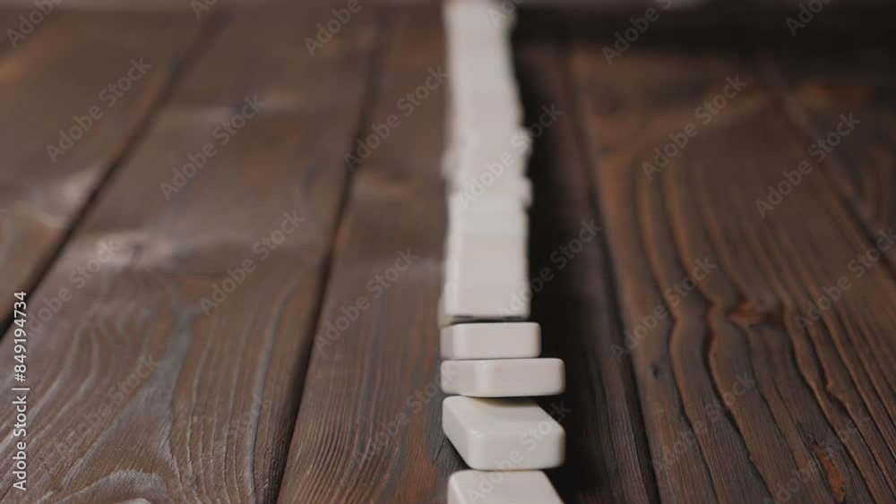 Close-up of a line of falling dominoes on a wooden surface. Domino Effect Concept. Concept of domino effect and chain reaction.