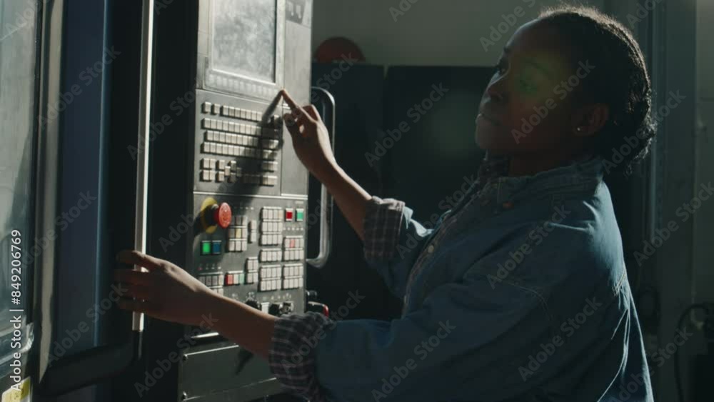 African American female industrial machine operator using control panel ...
