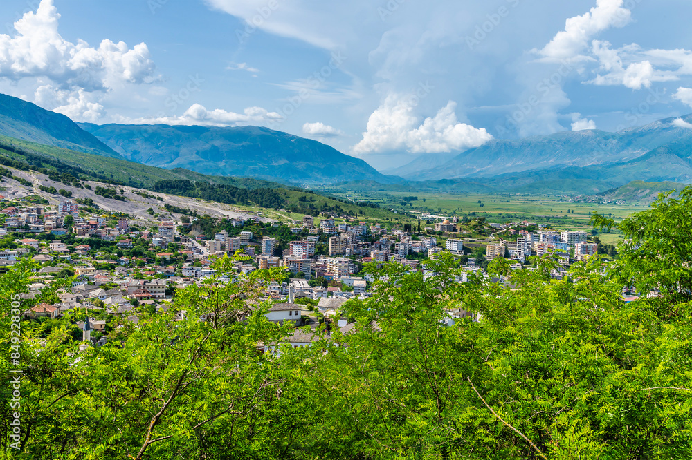 Obraz premium A view from the castle past trees towards the city of Gjirokaster, Albania in summertime
