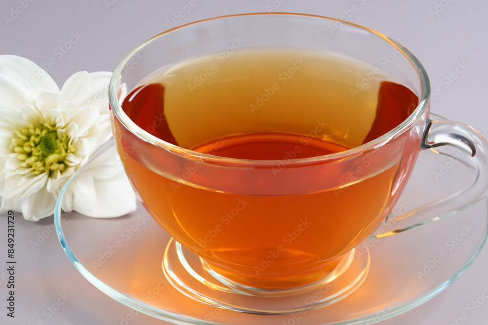 tea with flower. on a gray table there is a small transparent mug of tea with a white flower nearby, top view closeup drink concept tea with flower. on a gray table there is a small transparent mug of tea with a white flower nearby, top view closeup drink concept