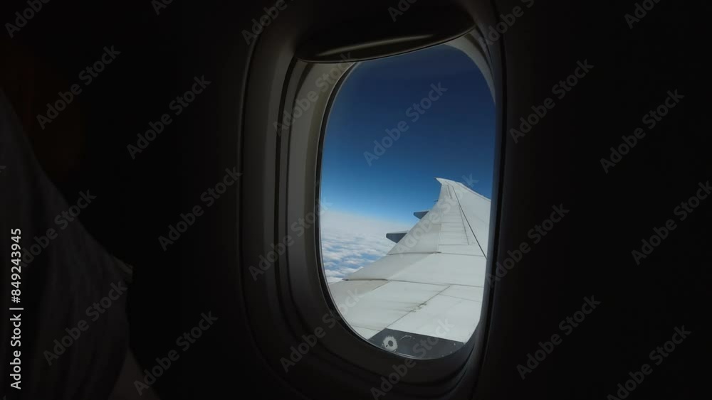 The camera captures the window of the aircraft from the inside during a high-altitude flight on a clear sunny day. The beginning of the journey, air travel. It's dark in the cabin of the plane The camera captures the window of the aircraft from the inside during a high-altitude flight on a clear sunny day. The beginning of the journey, air travel. It's dark in the cabin of the plane