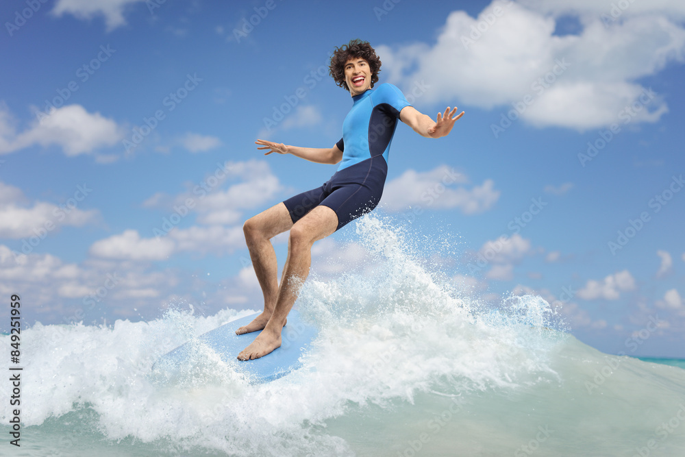 Young man in a wetsuit riding a surfboard on a wave Young man in a wetsuit riding a surfboard on a wave