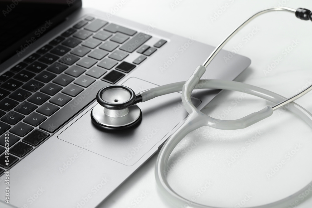 Modern laptop and stethoscope on white table, closeup Modern laptop and stethoscope on white table, closeup