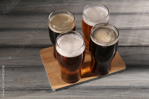 Glasses with different types of beer on grey wooden table