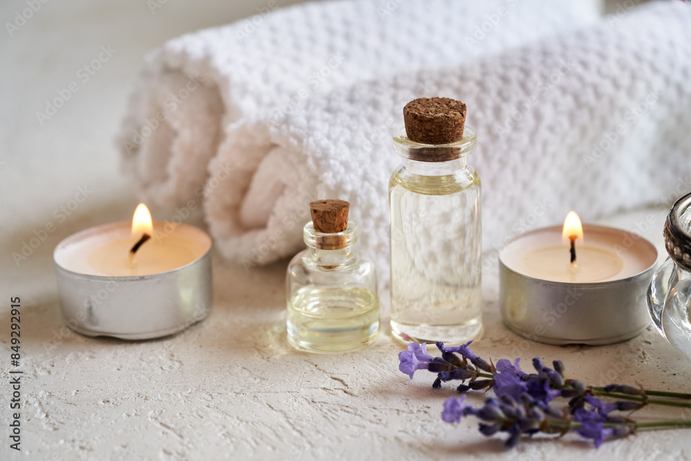 Transparent bottles of aromatherapy essential oil with lavender flowers, candles and spa treatment accessories on white Transparent bottles of aromatherapy essential oil with lavender flowers, candles and spa treatment accessories on white
