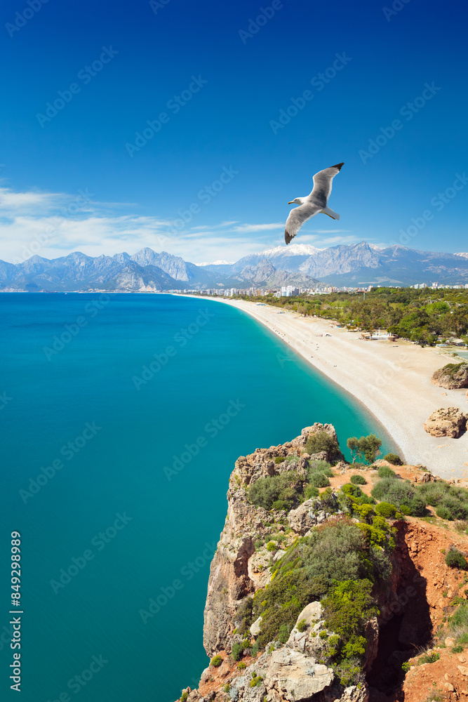 Obraz premium Serene turquoise waters of Mediterranean sea and Konyaalti beach, framed by mountains and deep blue sky in Antalya, Turkey. Welcome to Antalya concept image