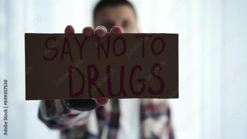 A man is holding a sign that says SAY NO TO DRUGS.
A man protests against drugs.
A man holding a corton sign, protesting against drug use