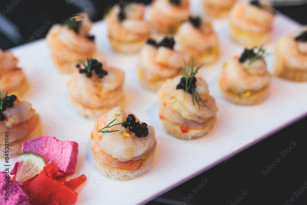 Beautifully decorated banquet catering table, with variety of with different food snacks appetizers on corporate birthday party event or wedding celebration, canape, salad, delicatessen setting Beautifully decorated banquet catering table, with variety of with different food snacks appetizers on corporate birthday party event or wedding celebration, canape, salad, delicatessen setting