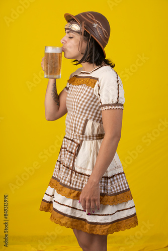 Beautiful young woman wearing typical ''festa junina'' costume holding a mug of cold beer photo