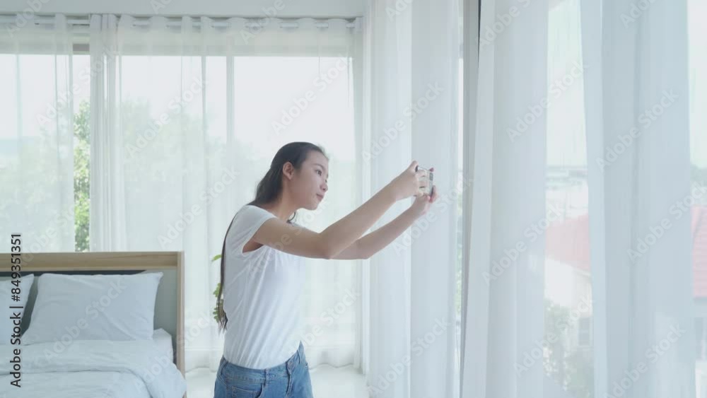 Woman on windowsills and takes pictures. View of young female looking at dawn city scenery in window.