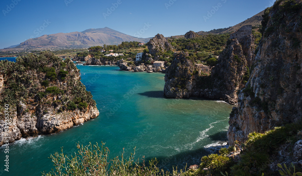 View across tranquil cove to the Faraglioni, Scopello
