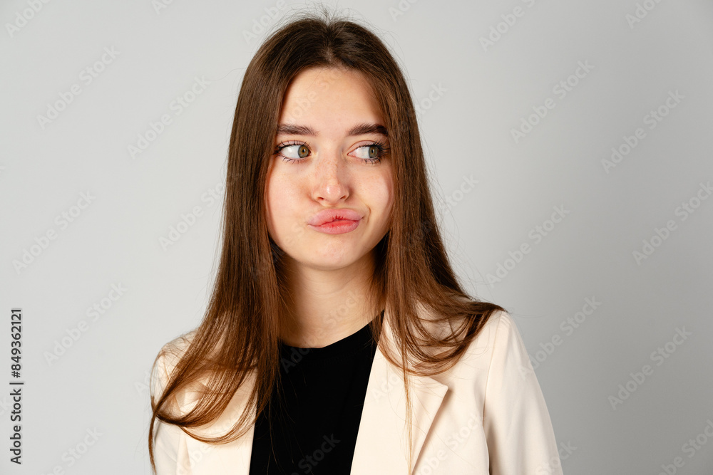 Young Woman Making a Playful Face Against a Gray Background in a Studio Young Woman Making a Playful Face Against a Gray Background in a Studio