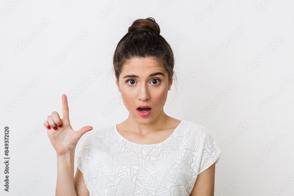 close up portrait of young shocked woman in white blouse pointing finger up, emotional, having idea, surprised face expression, looking into camera, isolated on studio background close up portrait of young shocked woman in white blouse pointing finger up, emotional, having idea, surprised face expression, looking into camera, isolated on studio background