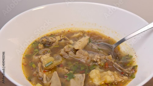Close-Up of Spoon Lifting Beef Offal from Spicy Isaan Soup (Tom Saep) - Thai Cuisine